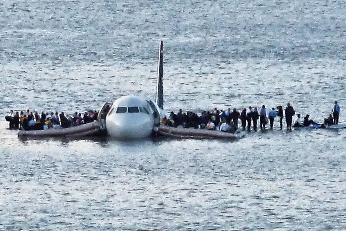 Parados en las alas del avión, los pasajeros aguardan el rescate minutos después de haber amerizado