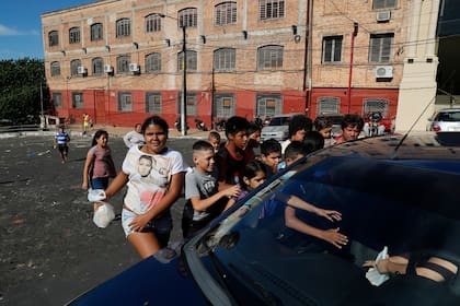 Los niños buscan comida entregada por una mujer en un automóvil que pasa en el barrio pobre de Chacarita en Asunción