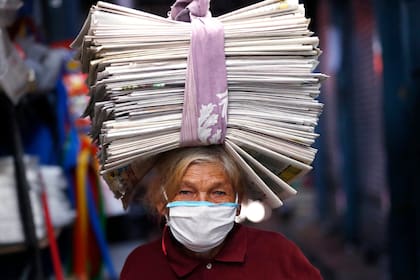 Guillermina de Figueredo, de 72 años, balancea periódicos reciclados en su cabeza que vende a comerciantes que los usan como envoltorios