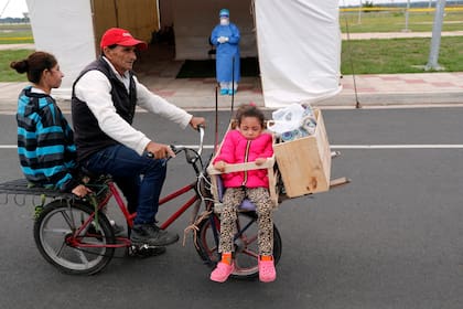 Una familia espera en su bicicleta para hacerse la prueba de COVID-19 en un sitio de prueba móvil en Asunción, Paraguay