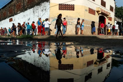 Los vecinos hacen fila para obtener alimentos básicos gratuitos fuera de la escuela primaria de Santa Ana