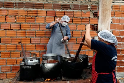 Walter Ferreira y Laura Dure cocinan estofado en un comedor comunitario que alimenta a unas 300 personas diariamente en Luque