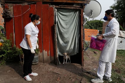 Dos trabajadores del Ministerio de Salud esperan a que el ocupante salga para hacerse la prueba del COVID-19 en Limpio, Paraguay, finalmente la enfemera entró con equipo de protección, por que la mujer que estaba adentro estaba muy enferma
