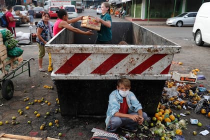 Con su familia, Fabián Ramírez, de 11 años, recolecta vegetales de un contenedor de basura desechados en el "Mercado de Abasto"