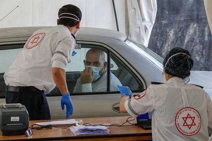 Paramédicos del servicio de emergencia nacional Magen David Adom de Israel, se preparan para examinar a un hombre por Covid-19 en el vecindario Jabal Mukaber