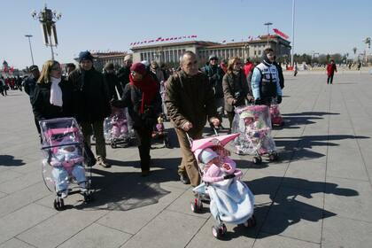 Parejas españolas sacan a pasear a sus niños chinos recién adoptados en la Plaza Tiananmen de Beijing el 7 de marzo del 2007. (Foto AP /Greg Baker)