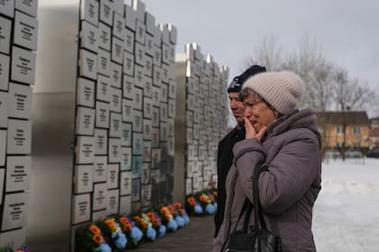 Parientes de fallecidos durante la ocupación rusa lloran en el Muro de Recuerdo durante una ceremonia para conmemorar el cuarto aniversario de la invasión rusa (Archivo)