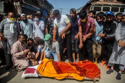 Parientes y vecinos se lamentan cerca del cadáver de Bashir Ahmad, un civil muerto durante un enfrentamiento entre agentes y rebeldes en Sopore, a 55 kilómetros (34 millas) al norte de Srinagar, en la parte de Cachemira controlada por India, el sábado 12 de junio de 2021. (AP Foto/Mukhtar Khan)