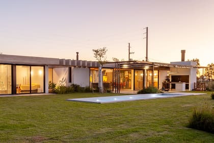 Parrilla con barra de hormigón alisado. Alrededor de la pérgola de caño con techo de acrílico instalaron toldos transparentes.
