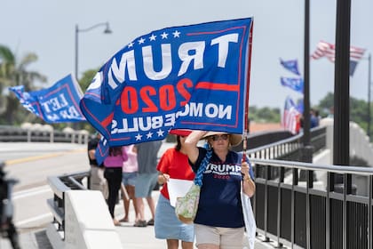 Partidarios de Donald Trump blanden banderas con su nombre cerca de la mansión Mar-a-Lago, en Palm Beach