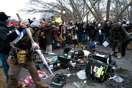Partidarios de Donald Trump rompen equipos de televisión frente al Capitolio de Estados Unidos el 6 de enero de 2021, en Washington.