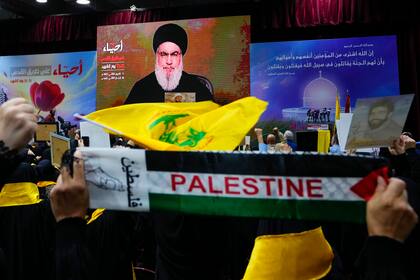 Partidarios de la milicia Hezbollah saludan con el puño en alto al escuchar un discurso del dirigente Hassan Nasrallah por video en el "Día de los Mártires de Hezbollah" en el suburbio de Dahiyeh al sur de Beirut, Líbano, sábado 11 de noviembre de 2023. (AP Foto/Hassan Ammar)