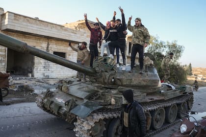 Partidarios de la oposición siria celebran arriba de un tanque de guerra del Ejército sirio en el poblado de Maarat al-Numan