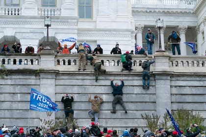 Partidarios de Trump suben por el muro oeste del Capitolio de Estados Unidos, en Washington, el 6 de enero de 2021