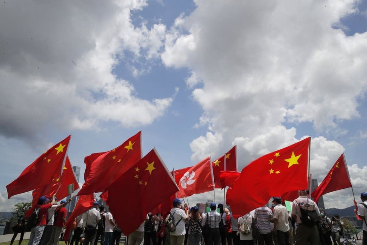 Partidarios del gobierno chino sostienen banderas de China y Hong Kong durante una manifestación para celebrar la aprobación de la ley,