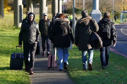 Pasajeros caminan rumbo al aeropuerto Gatwick, donde se registraron cancelaciones y retrasos de vuelos tras el hallazgo de un "artículo prohibido sospechoso" en el equipaje de un pasajero, en Crawley, Inglaterra, el viernes 22 de noviembre de 2024. (Gareth Fuller/vía AP)