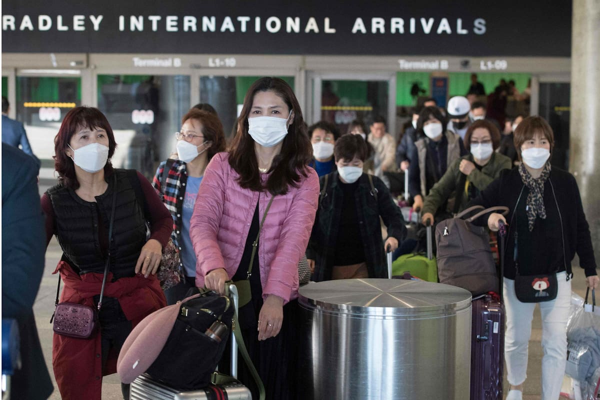 Pasajeros con barbijo en la sala de arribos del aeropuerto de Los Ángeles
