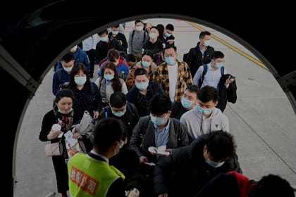 Pasajeros con mascarillas abordan un avión en el Aeropuerto Internacional Shenzhen Baoan en la ciudad de Shenzhen, en el sureste de China, el 29 de diciembre de 2020