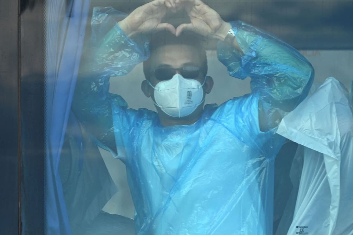 Pasajeros del crucero MV Hondius, afectado por un brote de hantavirus, gesticulan dentro de un colectivo militar tras desembarcar en el puerto de Granadilla de Abona, en la isla de Tenerife