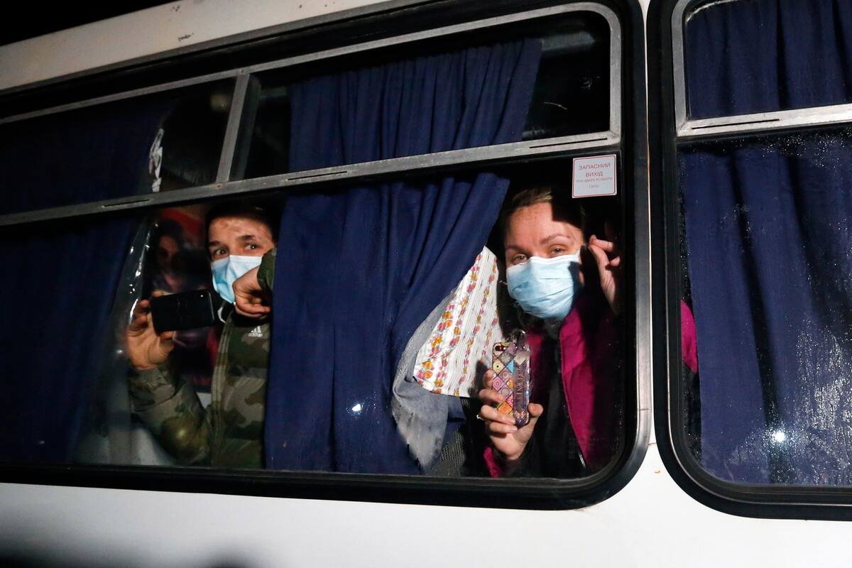 Pasajeros evacuados de la ciudad china de Wuhan, miren por la ventana de un autobús afuera de Novi Sarzhany, Ucrania, el jueves 20 de febrero de 2020.
