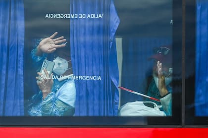 Pasajeros evacuados del crucero MV Hondius saludan desde un autobús militar tras ser trasladados al puerto de Granadilla de Abona, en Tenerife, el 10 de mayo de 2026
(Photo by JORGE GUERRERO / AFP)
