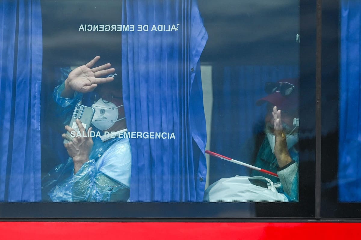 Pasajeros evacuados del crucero MV Hondius, de bandera holandesa y afectado por un brote de hantavirus, saludan desde un micro militar tras ser trasladados en lancha al puerto industrial de Granadilla de Abona, en la isla de Tenerife, en las Islas Canarias de España, el 10 de mayo de 2026