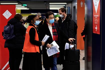 Pasajeros procedentes de China aguardan frente a una zona de pruebas de COVID-19 en el aeropuerto Roissy Charles de Gaulle, al norte de París, el domingo 1 de enero de 2023. (AP Foto/Aurelien Morissard)