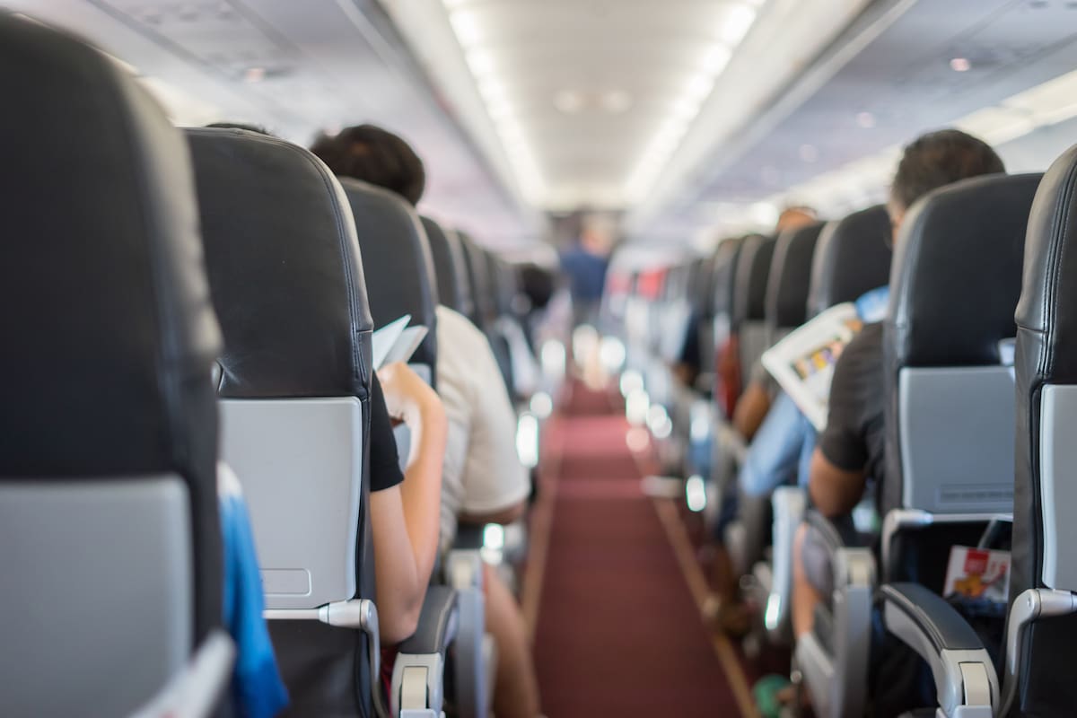 passenger seat, Interior of airplane with passengers sitting on seats and stewardess walking the aisle in background. Travel concept,vintage color