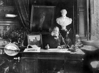 Pastor Obligado retratado en su escritorio, a su lado una pintura de su residencia sobre Avenida Alvear, circa 1886.