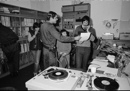 Patrick Watts, en la radio de Malvinas, delante de un militar argentino en 1982; Wollmann tomó la foto