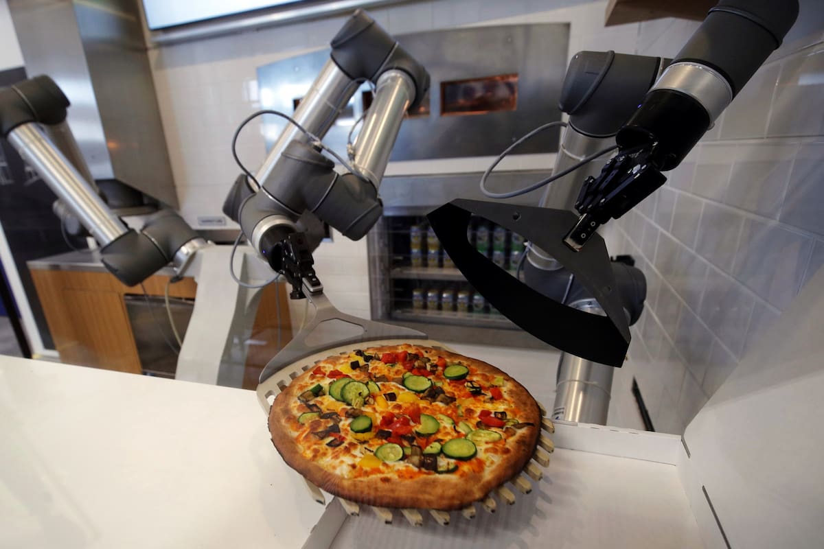 Pazzi arma la pizza con los ingredientes pedidos, la mete al horno, la saca, la corta en porciones y la pone en la caja