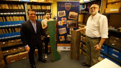 Pedro Orgambide, presidente del Departamento de Fútbol Amateur de Boca, y Guillermo Schoua y Sergio Brignardello, responsables de la Subcomisión de Historia del club de la Ribera, posan con los dos tablones recuperados