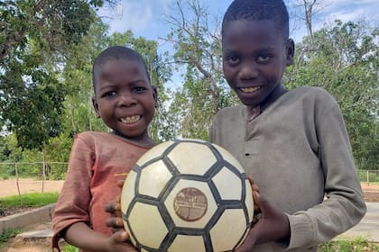 Una de las pelotas hechas por presos de una cárcel bonaerense en manos de dos niños de Mozambique