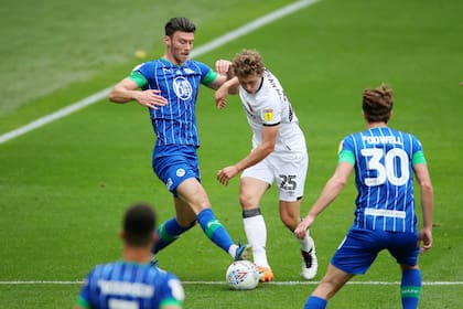 Pennington, lateral de Hull City, lucha en soledad ante entre dos jugadores de Wigan