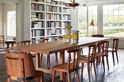 Pensada para grandes reuniones, en el comedor se impone una mesa de madera clara para diez personas y una biblioteca de piso a techo.