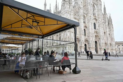 People have a lunch at a terrace in Duomo square on April 26, 2021 in central Milan. - Bars, restaurants, cinemas and concert halls will partially reopen across Italy Monday in a boost for coronavirus-hit businesses, as parliament debates the government's 220-billion-euro ($266-billion) EU-funded recovery plan. After months of stop-start restrictions imposed to manage its second and third waves of Covid-19, Italy hopes this latest easing will mark the start of something like a normal summer. (Photo by Miguel MEDINA / AFP)