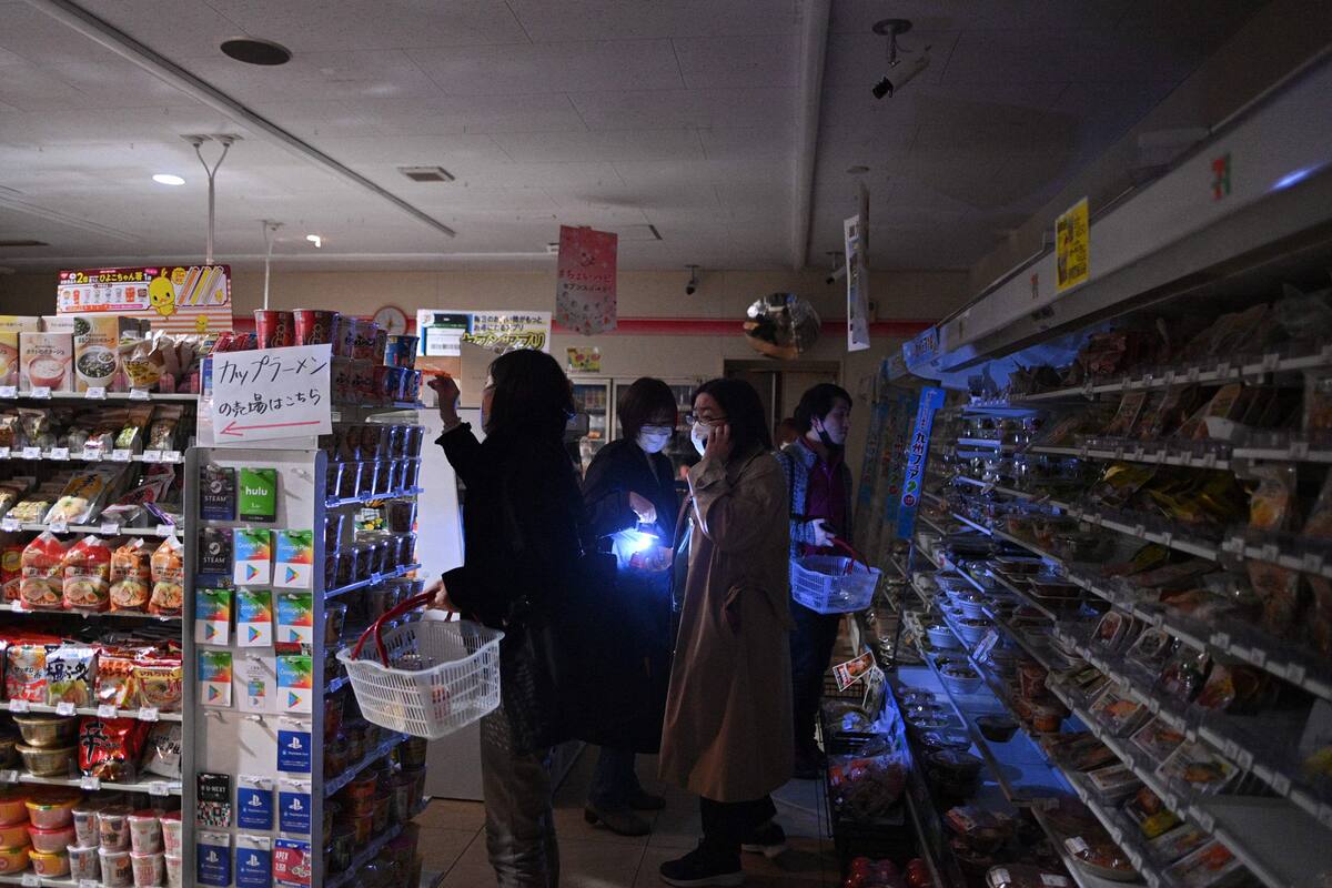 People shop in a store in a residential area during a power outage in Koto district in Tokyo on March 16, 2022, after a powerful 7.3-magnitude quake jolted east Japan. (Photo by Philip FONG / AFP)