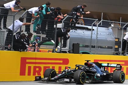Lewis Hamilton cruza la línea de llegada con su Mercedes, mientras su equipo celebra