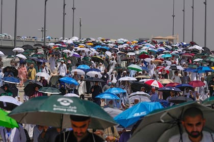 Peregrinos musulmanes utilizan paraguas para protegerse del sol