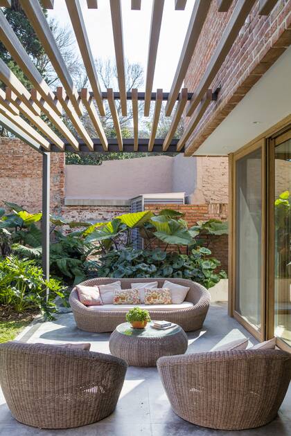 Pérgola con listones de WPC (Sólido Carpintería). Piso de hormigón pulido. Juego de living de plástico símil ratán (Jumbo).