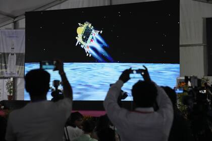 Periodistas filman la retransmisión en directo del alunizaje de la nave espacial Chandrayaan-3 en las instalaciones de Telemetría, Seguimiento y Red de Mando de ISRO en Bengaluru, India, el miércoles 23 de agosto de 2023. India aterriza una nave espacial cerca del polo sur de la Luna, convirtiéndose en el cuarto país en tocar la superficie lunar. (AP Photo/Aijaz Rahi)