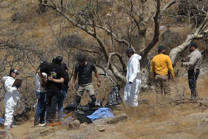 Peritos forenses trabajan con varias bolsas de restos humanos extraídos del fondo de una quebrada por un helicóptero, el 31 de mayo de 2023