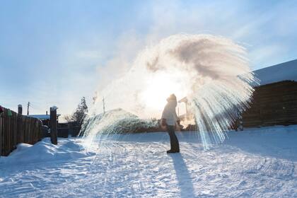 Persona vertiendo agua caliente que se congela inmediatamente en Oymyakon, Yakutia
