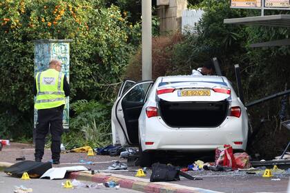 Personal de emergencia israelí trabaja junto a un auto dañado tras un ataque con embestida en Raanana el 15 de enero de 2024.