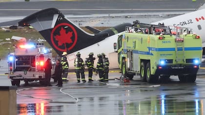 Personal de emergencia trabaja mientras un avión CRJ-900 de Air Canada Express permanece en la pista tras colisionar con un camión de bomberos de la Autoridad Portuaria en el aeropuerto LaGuardia de Nueva York, el 23 de marzo de 2026