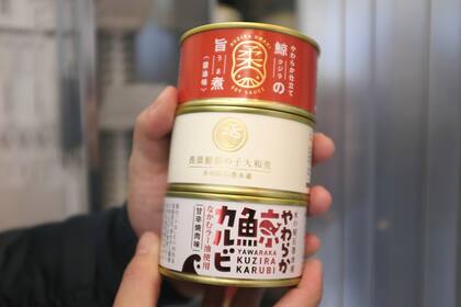 Personal de Kyodo Senpaku Co. muestra latas de carne de ballena adquirida en una máquina expendedora de la tienda de la compañía, el jueves 26 de enero de 2023, en Yokohama, Japón. (AP Foto/Kwiyeon Ha)