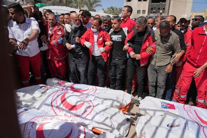 Personal de la Media Luna Roja se reúnen alrededor de los cadáveres de 8 integrantes del personal de emergencia de la Media Luna Roja, recuperados en Rafah una semana después de un ataque de soldados israelíes, al momento de ser transportados para su entierro de un hospital en Deir al-Balah, en la Franja de Gaza, el lunes 31 de marzo de 2025.
