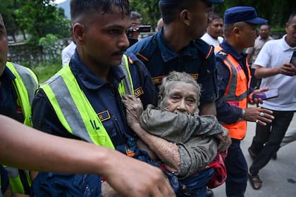 Personal de rescate traslada a una persona afectada por las inundaciones repentinas en Devghat, en el distrito nepalí de Nuwakot, el 26 de agosto de 2026 (Prakash Mathema/ AFP)