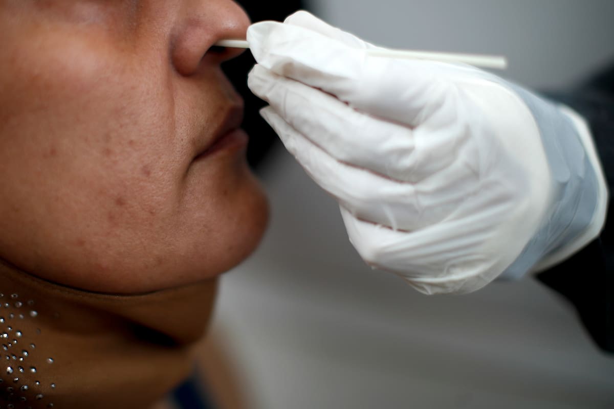 Personal de salud efectúa un hisopado en una cabina de un hospital de Buenos Aires.