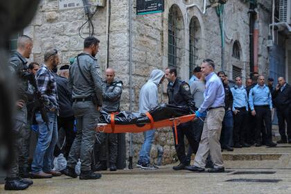 Personal de seguridad israelí y miembros del equipo Zaka de Rescate y Recuperación trasladan el cuerpo de un palestino baleado por la policía israelí tras un ataque en el que mató a una persona e hirió a cuatro en la zona antigua de Jerusalén, el domingo 21 de noviembre de 2021. (AP Foto/Mahmoud Illean)